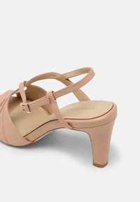 Pink high-heeled sandal with cross straps, a rounded toe, and a buckle closure. Smooth synthetic material with a textured insole.