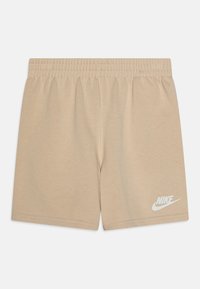 Kreminės spalvos medvilninės šortai su elastinga juosta. Apačioje kairėje pusėje yra balta Nike logo. Lygi tekstūra, paprastas dizainas, be kišenių.