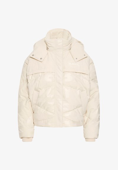 Krēmveida pūkaina jaka ar augstu apkakli, sprādzēm, priekšējām kabatām un tonālām logotipa detaļām. Izgatavota no vatēta, gluda auduma.