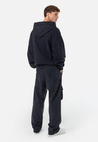 Mørkegrå hættetrøje med en afslappet pasform og kængurulomme, parret med matchende joggerbukser med sidelommer og en løs silhuet.
