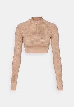 Long-sleeve crop top in a light beige, featuring textured diamond pattern, quarter zip closure, and fitted sleeves with ribbed cuffs.