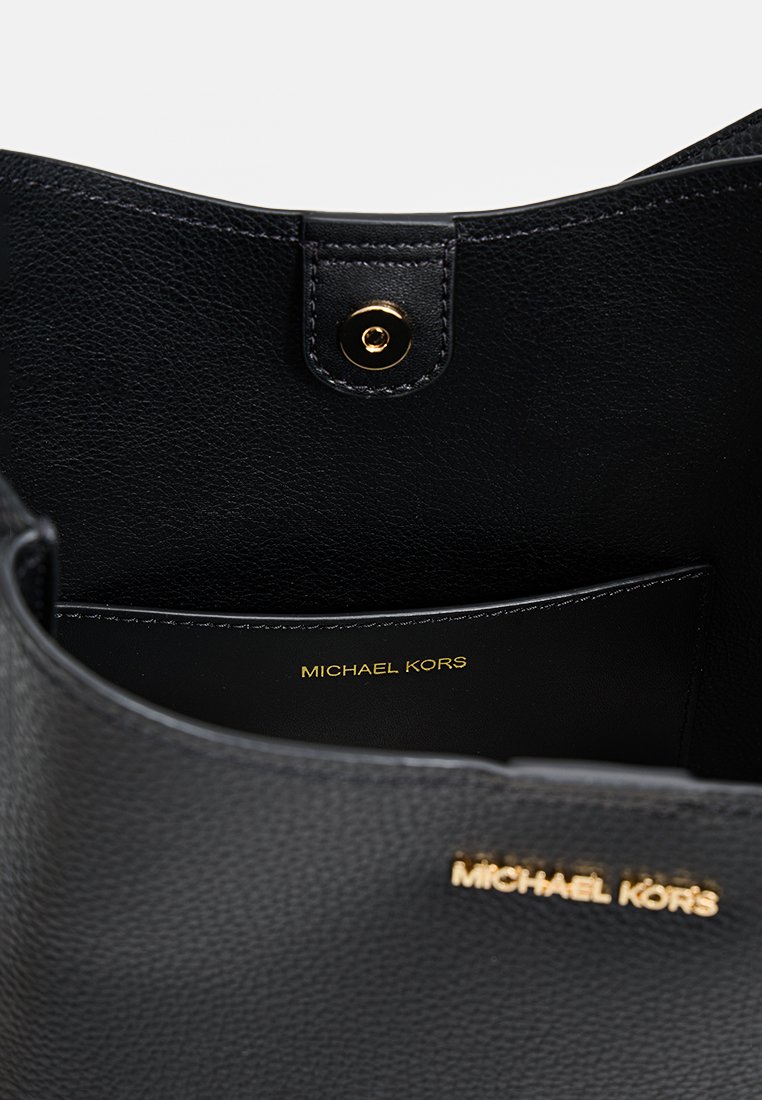 Schwarze Lederhandtasche mit strukturiertem Innenfutter. Verfügt über einen goldenen Druckverschluss und das eingestempelte "MICHAEL KORS"-Logo auf der Innenausstattung.