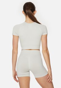 Light gray athletic crop top and high-waisted shorts, made of stretchy, textured material with a close fit and short sleeves.