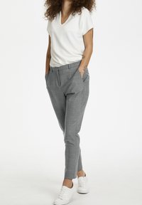 Grå skräddarsydda byxor med ett subtilt rutmönster, smal passform, sidofickor, tillsammans med en vit t-shirt med v-ringning och vita sneakers.