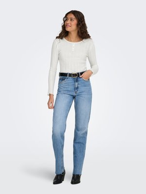 White ribbed long-sleeve top with three buttons, paired with light blue straight-leg jeans and black ankle boots.