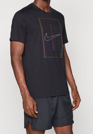 Mężczyzna noszący czarną koszulkę Nike z wielokolorowym prostokątnym wzorem i białym znakiem Nike swoosh, w połączeniu z czarnymi szortami.