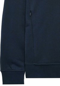 Felpa blu navy con tessuto a maglia testurizzato, dotata di tasca laterale con zip e polsini a costine. Il design include linee pulite e bordi senza cuciture.