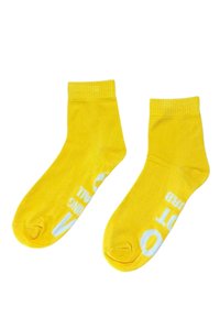 Calcetines de algodón amarillos con un puño acanalado, que presentan texto blanco y un logo redondo. Tienen una textura suave y un diseño de longitud hasta el tobillo.