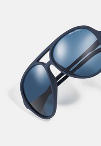 Ochelari de soare bleumarin cu o finisare mată, de formă aviator supradimensionată, cu lentile reflectorizante albastre. Prezintă un design cu decupaje pe ramă.