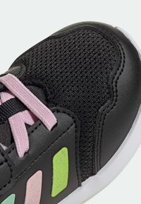 Baskets noires avec une tige en mesh texturé. Dotées de lacets roses et d'accents brillants verts, roses et bleus sur le côté. Semelle en caoutchouc blanche.