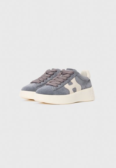 Grijze suède sneakers met dikke vuilwitte zolen en bijpassende veters, voorzien van een witte "H"-logo aan de zijkant.