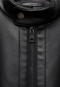 Czarna skórzana kurtka z wysokim kołnierzem, centralnym zamkiem błyskawicznym ze srebrnymi elementami oraz przeszyciami wzdłuż boków.