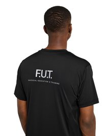 Mann mit kurzen Haaren und goldenen Creolen, der ein schwarzes T-Shirt mit dem Schriftzug „F.U.T. Physical Education & Training“ trägt, von hinten vor weißem Hintergrund.