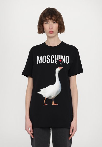 Polo negru din bumbac cu un grafic alb de gâscă și textul „MOSCHINO”. Are mâneci scurte și o croială lejeră.