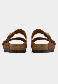 Καφέ, ανοιχτά σανδάλια με μοτίβα ζώων, δύο λουριά που σχηματίζουν βρόχους και υφή φελλού στη σόλα. Μαύρη λαστιχένια εξωτερική σόλα για καλύτερη πρόσφυση.