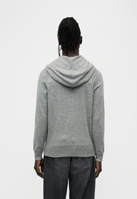 Sweat à capuche gris en matière douce, avec une coupe décontractée, des poignets et un ourlet côtelés, ainsi qu'un décolleté profond pour plus de confort.