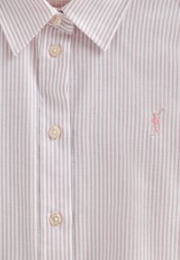 Camicia bianca con strette righe rosa, colletto button-down e bottoni beige. Presenta un piccolo logo ricamato rosa sul petto.
