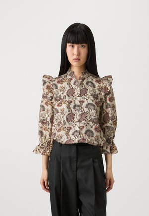 Blusa con fantasia floreale in crema, con dettagli arricciati sulle spalle e chiusura con bottoni. Abbinata a pantaloni neri a vita alta. Tessuto texture.