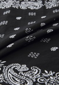 Black fabric with white paisley and geometric prints, featuring a soft texture. The design includes intricate patterns and flowing shapes.