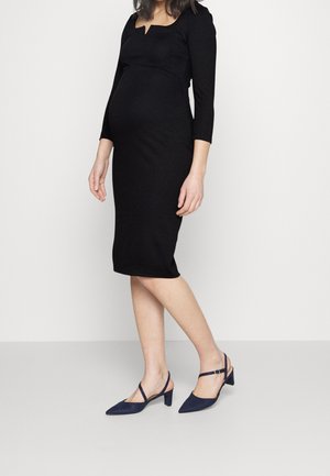 Abito da maternità nero con scollatura quadrata e maniche a tre quarti, abbinato a décolleté slingback blu navy con tacco a blocco basso.