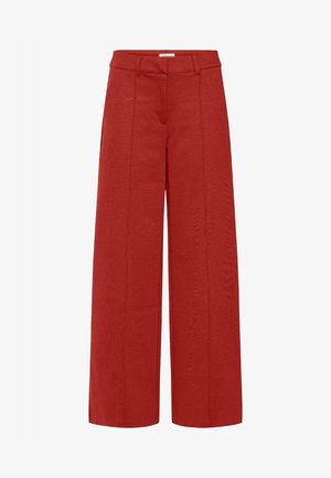 Laiad püksid erksast punasest kangast, millel on sile tekstuur ja esimesed õmblused lisadetailiks, klassikalise kummivööga.