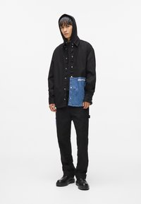 Melns kapuci jakas ar denima kabatu detaļām; melnas bikses ar sānu kabatām; melnas kurpes; gluda tekstūra, mūsdienīgs dizains.