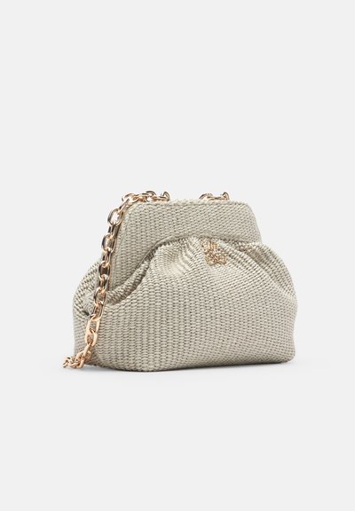 Sac à main beige en tissu tressé avec une bandoulière en chaîne dorée et une petite boucle décorative dorée sur un fond blanc uni.
