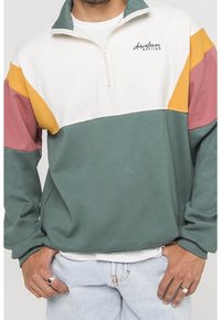 Felpa con mezza zip, caratterizzata da blocchi di colore bianco, giallo, rosa e verde. Materiale morbido e vestibilità rilassata. Logo sul petto.