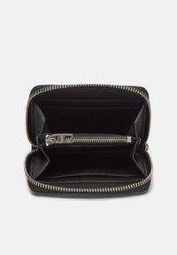 Czarny skórzany portfel z srebrnym zamkiem błyskawicznym i okuciami, wyposażony w wiele miejsc na karty oraz centralną kieszeń zapinaną na zamek. Miękka faktura, minimalistyczny design.