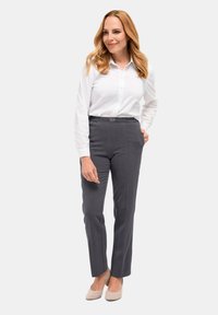 Grijze op maat gemaakte broek met een rechte pijp en elastische tailleband, gecombineerd met een witte katoenen overhemd met lange mouwen en knoopsluiting. Neutrale schoenen.