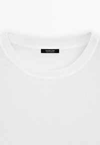 Witte ronde hals t-shirt met het zwarte label "Massimo Dutti Made in Morocco" genaaid aan de binnenkant van de hals.