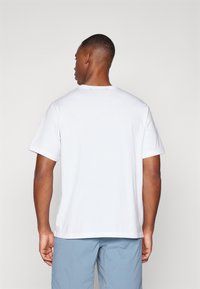 White short-sleeved T-shirt made of cotton. Features a round neckline and a relaxed fit, visible stitching along the hem and sleeves.