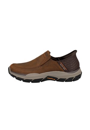 Zapato casual marrón tipo slip-on con talón acolchado, suela beige y dibujo negro con la marca Goodyear en el lateral.