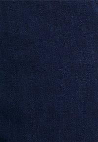 Tela de denim azul oscuro con una textura suave y un ligero brillo, que presenta un patrón de sarga y costuras mínimas visibles.