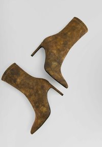 Brown suede ankle boots with a high stiletto heel, pointed toe, and smooth texture, featuring a fitted upper and subtle color variations.