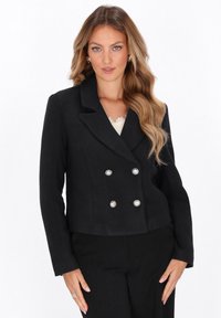 Blazer nero doppiopetto con colletto a lancia, bottoni argentati e design accorciato. Tessuto morbido, forma strutturata.