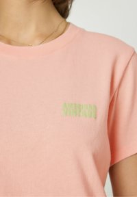 Pink cotton T-shirt with short sleeves and a crew neck. Features a light green embroidered "AMERICAN VINTAGE" logo on the left chest.