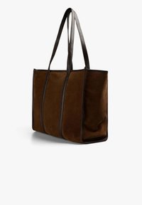 Bolso tote de ante marrón con ribetes de cuero oscuro, que cuenta con dos asas resistentes y un diseño estructurado con costuras visibles.