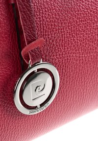 Rode leren tas met textuur, met een zilveren cirkelvormige Pierre Cardin logo charm bevestigd aan een leren hengsel.