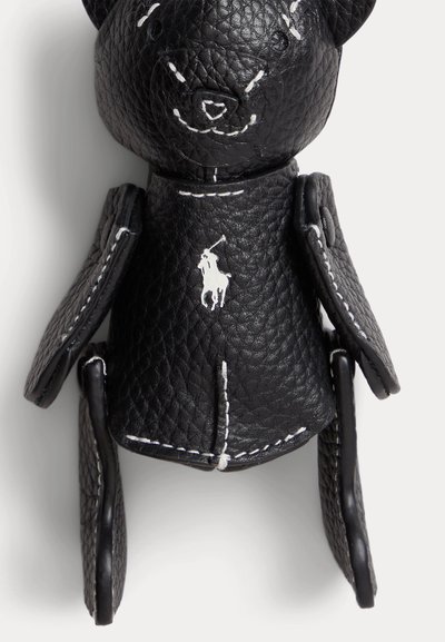 Μαύρο μπρελόκ αρκούδας από δερματίνη με λευκές ραφές και μικρό λευκό λογότυπο παίκτη πόλο στο στήθος της.