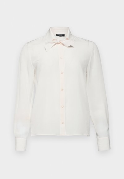 Bílá košile s dlouhými rukávy, mašlí na límci a knoflíkovým zapínáním. Hladká textura, jemná tkanina a slim fit s jemnými růžovými akcenty.