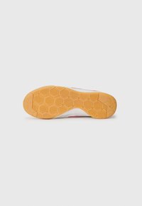 Schuhsohle mit einer strukturierten, orangen Gummifläche, die ein Wabenmuster aufweist und sich von einem weißen oberen Bereich mit roten Akzenten abhebt.