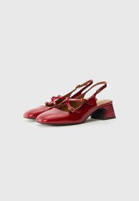 Escarpins à talons ouverts en cuir verni rouge avec un bout carré, une sangle ajustable et des boucles décoratives. Le talon texturé ajoute un intérêt visuel.