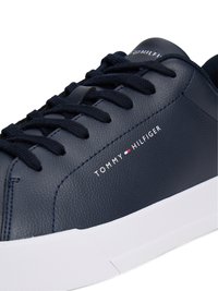 Sapatilha de couro azul marinho com superfície texturizada, sola de borracha branca e atacadores na mesma tonalidade. Apresenta o logótipo "TOMMY HILFIGER" em branco na lateral.