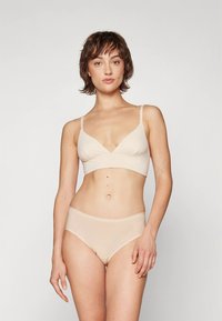 Beige bralette med tunna band och V-ringning, matchande trosor till. Mjukt, slätt tyg med sömlös design.