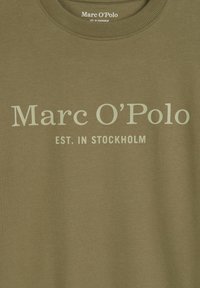 Olijfgroene sweatshirt van zachte stof. Heeft een ronde hals en bedrukt tekst: "Marc O'Polo EST. IN STOCKHOLM" in lichtgroen.