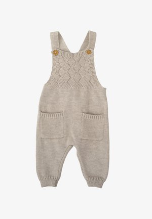 Combinaison en tricot beige avec un motif en torsade, bretelles réglables, deux poches avant et bordures côtelées aux chevilles. Fabriquée en matière douce et texturée.