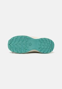 Light-colored sneaker sole with a textured, turquoise outsole featuring deep lugs for traction and stability. Smooth upper edge transition.