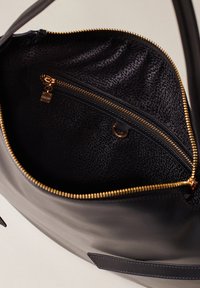 Borsa a mano in pelle nera con un interno testurizzato, caratterizzata da una chiusura lampo dorata e una piccola tasca con chiusura lampo. Esterno liscio, dettagli hardware minimi.