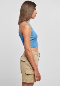 Blaues, kurzes Tanktop mit gerippter Textur, kombiniert mit khaki-farbenen Shorts mit Cargo-Taschen und geradem Schnitt, von der Seite gezeigt.